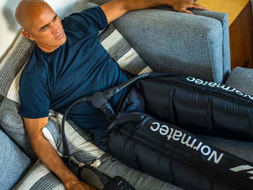 Man on chair using Normatec Compression boots therapy